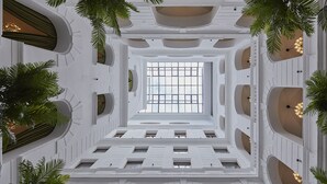 A grand atrium with a central open space, white walls, and multiple balconies with plants. - Mystery Hotel Budapest, Preferred Hotels & Resorts  (Budapest)