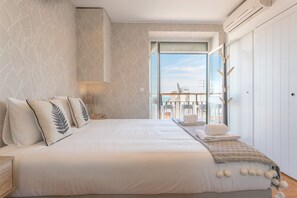 A bedroom with a large bed, a balcony with a view, and a wardrobe. - Alfama Vintage Studio Apartment w/ RiverView - by LU Holidays (Lisbon)