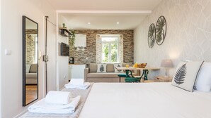 A modern hotel room with a large bed, a sofa, a dining area, and a kitchen. - Alfama Vintage Studio Apartment w/ RiverView - by LU Holidays (Lisbon)
