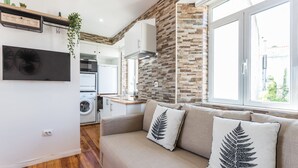 A modern kitchen with a built-in oven, a hanging plant, and a large window. - Alfama Vintage Studio Apartment w/ RiverView - by LU Holidays (Lisbon)