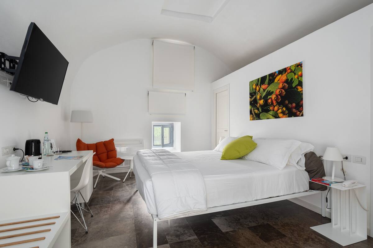 Een moderne hotelkamer met een bed, een bureau, een stoel, een televisie en een schilderij aan de muur.