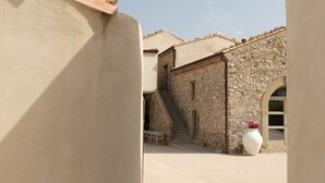 A courtyard with a stone building, a large white vase with flowers, and a clear blue sky.