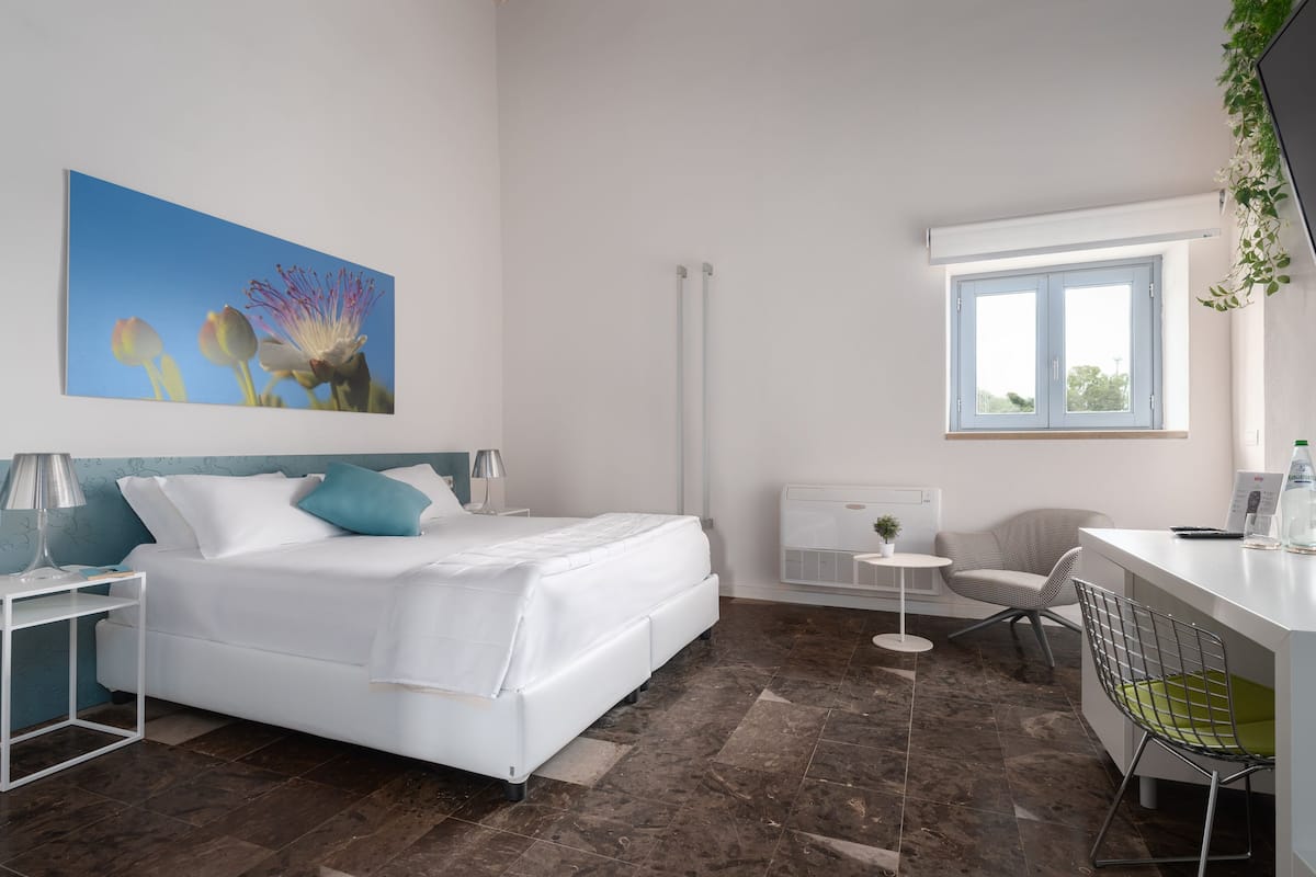 Een moderne hotelkamer met een bed, een bureau, een stoel en een raam.