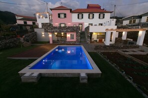 A residential property with a swimming pool, stone walls, and a garden.