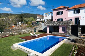 Ein modernes Haus mit Schwimmbad, Steinwänden und einem gepflegten Rasen.