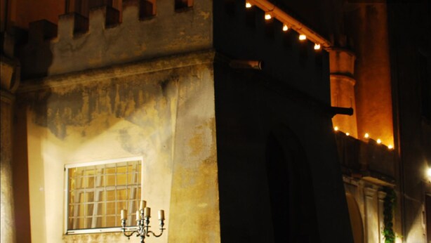 Fachada de um edifício histórico com uma janela e um candelabro.