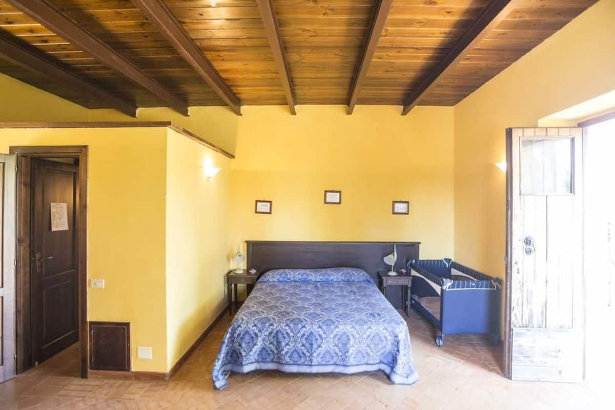 A bedroom with a bed, bedside tables, a bench, and a door.