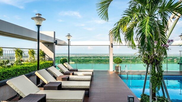 Un espace piscine aménagé sur le toit, avec des chaises longues, une piscine et une vue sur le paysage.