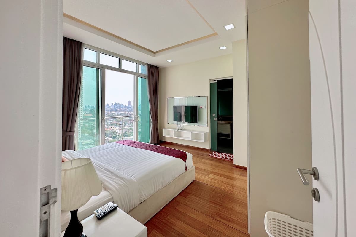 A hotel room with a large bed, a TV, and a city view.
