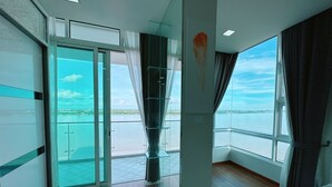 Une pièce spacieuse dotée d’une grande porte-fenêtre coulissante donnant sur un balcon avec vue sur l’eau.