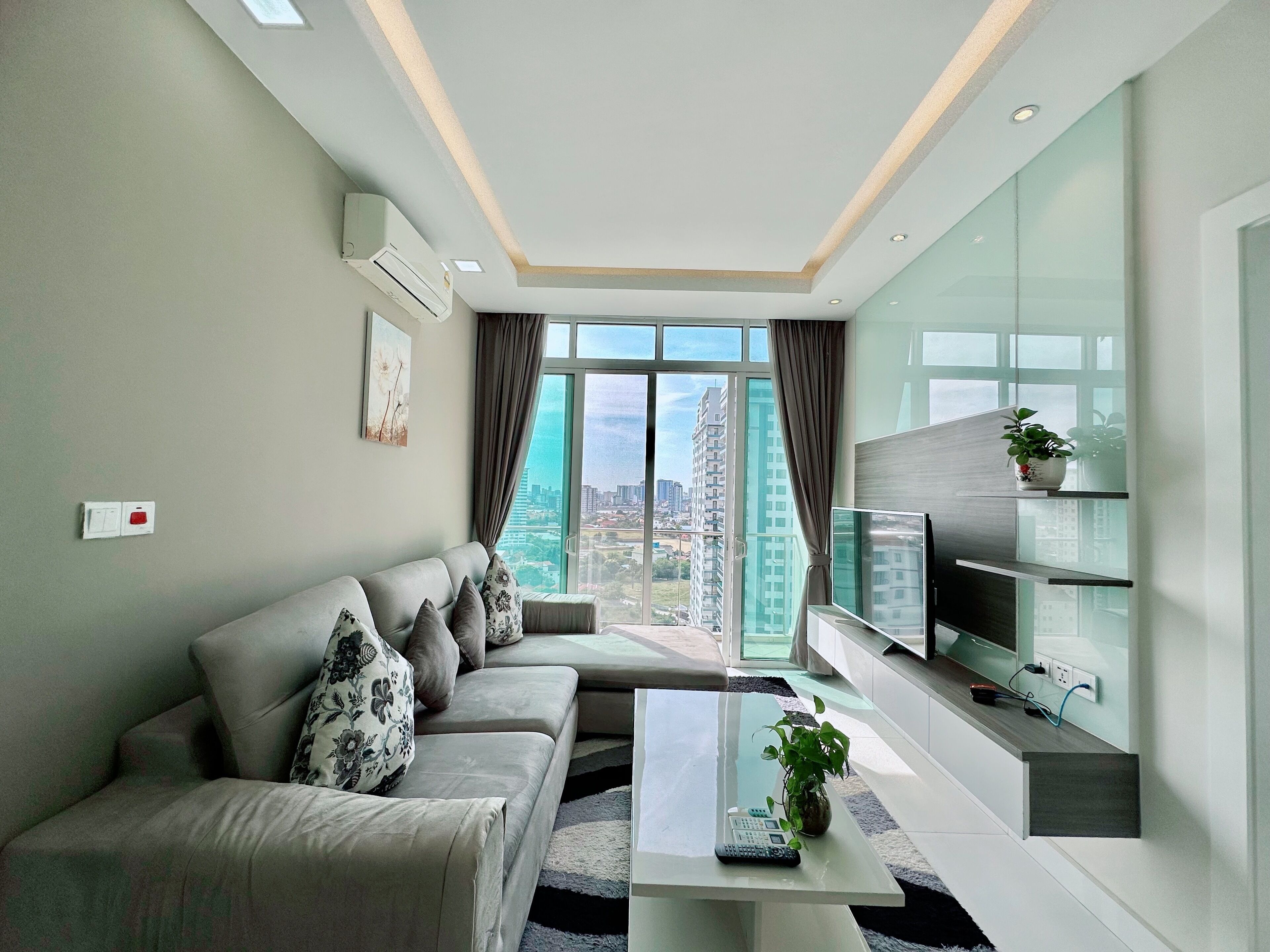 A modern living room with a sofa, a coffee table, and a TV on a wall-mounted shelf.