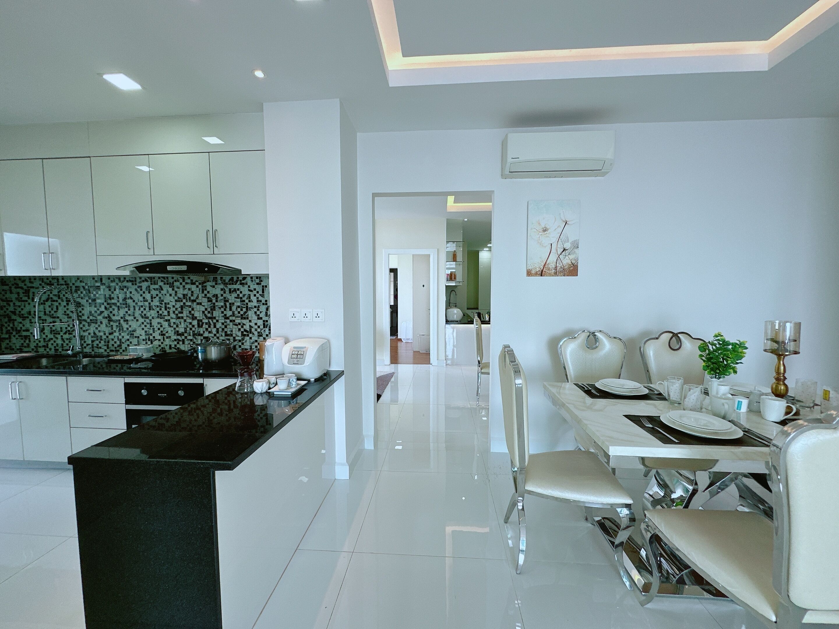A modern kitchen with white cabinets, a black countertop, and a dining area with a white table and chairs.