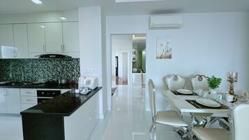 A modern kitchen with white cabinets, a black countertop, and a dining area with a white table and chairs.