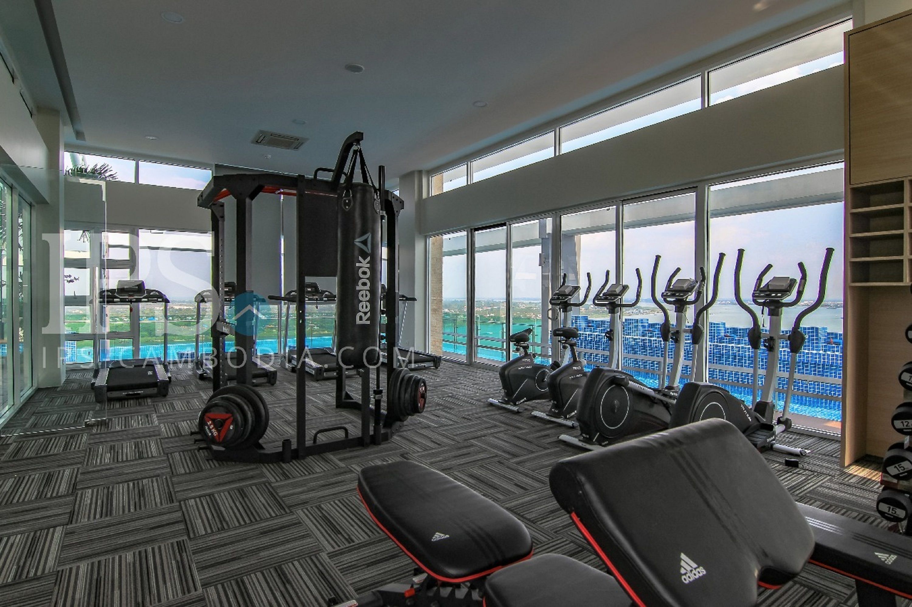 A gym with various exercise equipment, large windows, and a view of a cityscape.