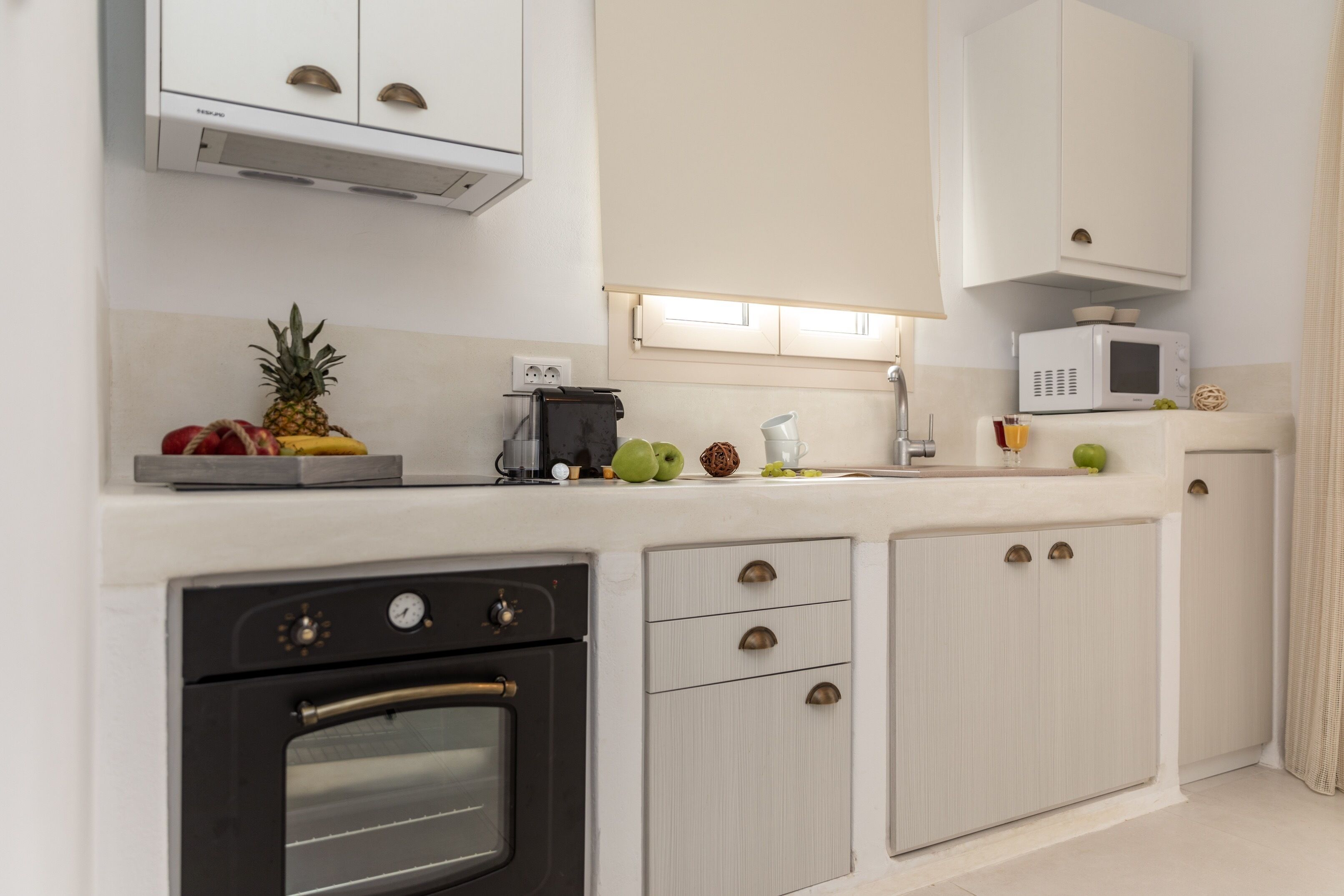 A modern kitchen with white cabinets, a black oven, a microwave, and a coffee maker.