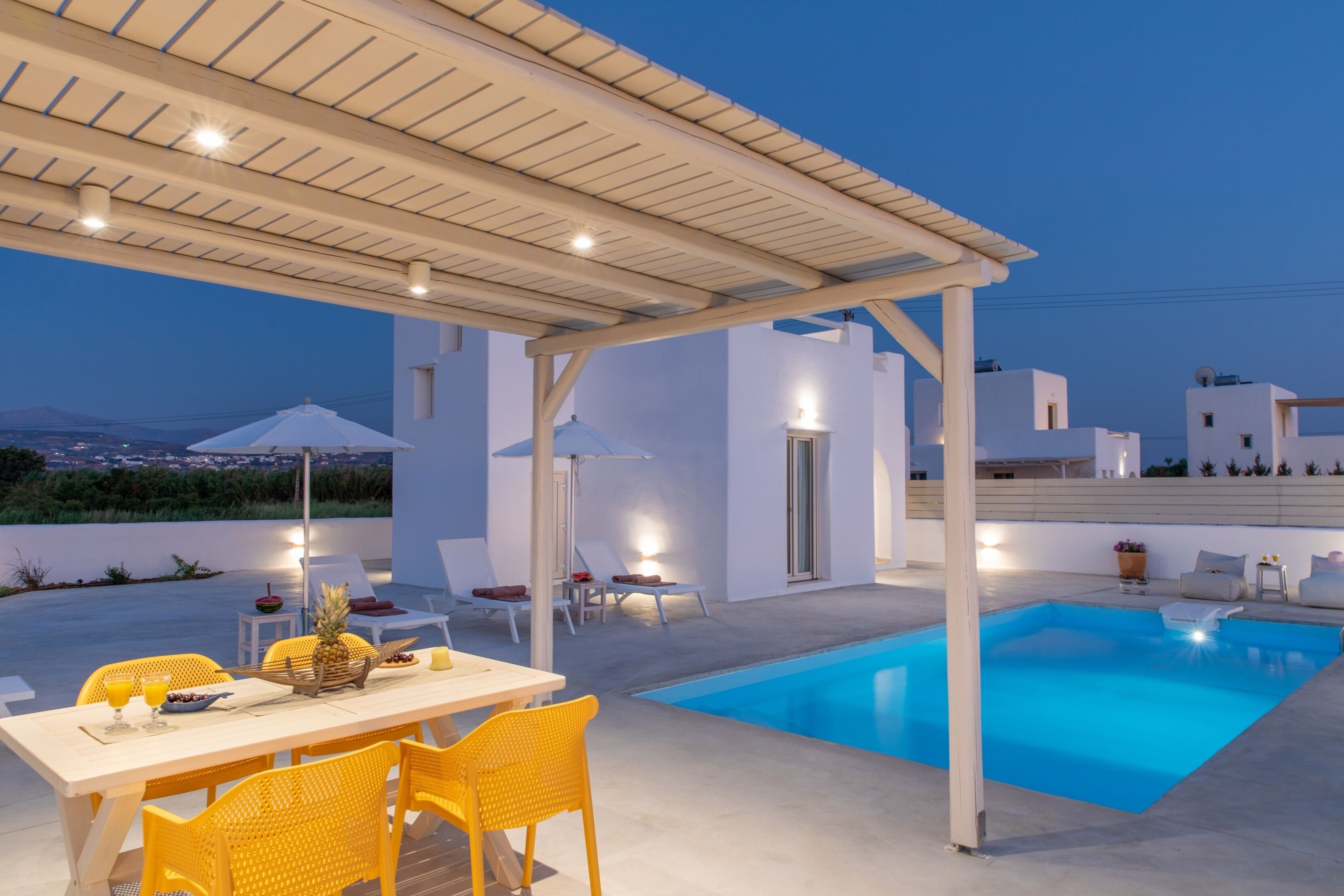 A modern outdoor pool area with a pergola, seating, and a dining table.