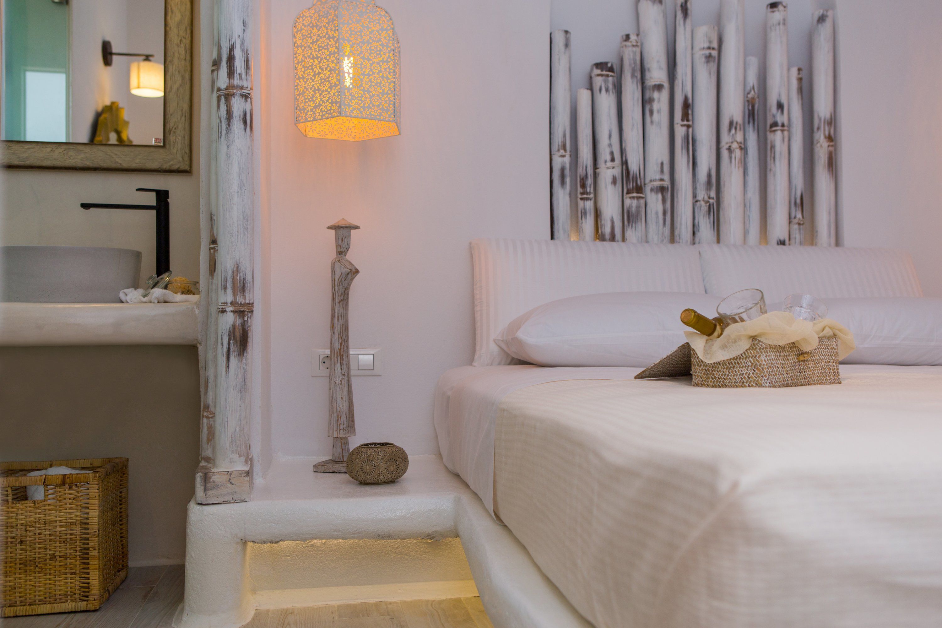 Ein Schlafzimmer mit einem Bett, einem Nachttisch, einer Lampe, einem Spiegel und einer Wand mit vertikalen Holzelementen.