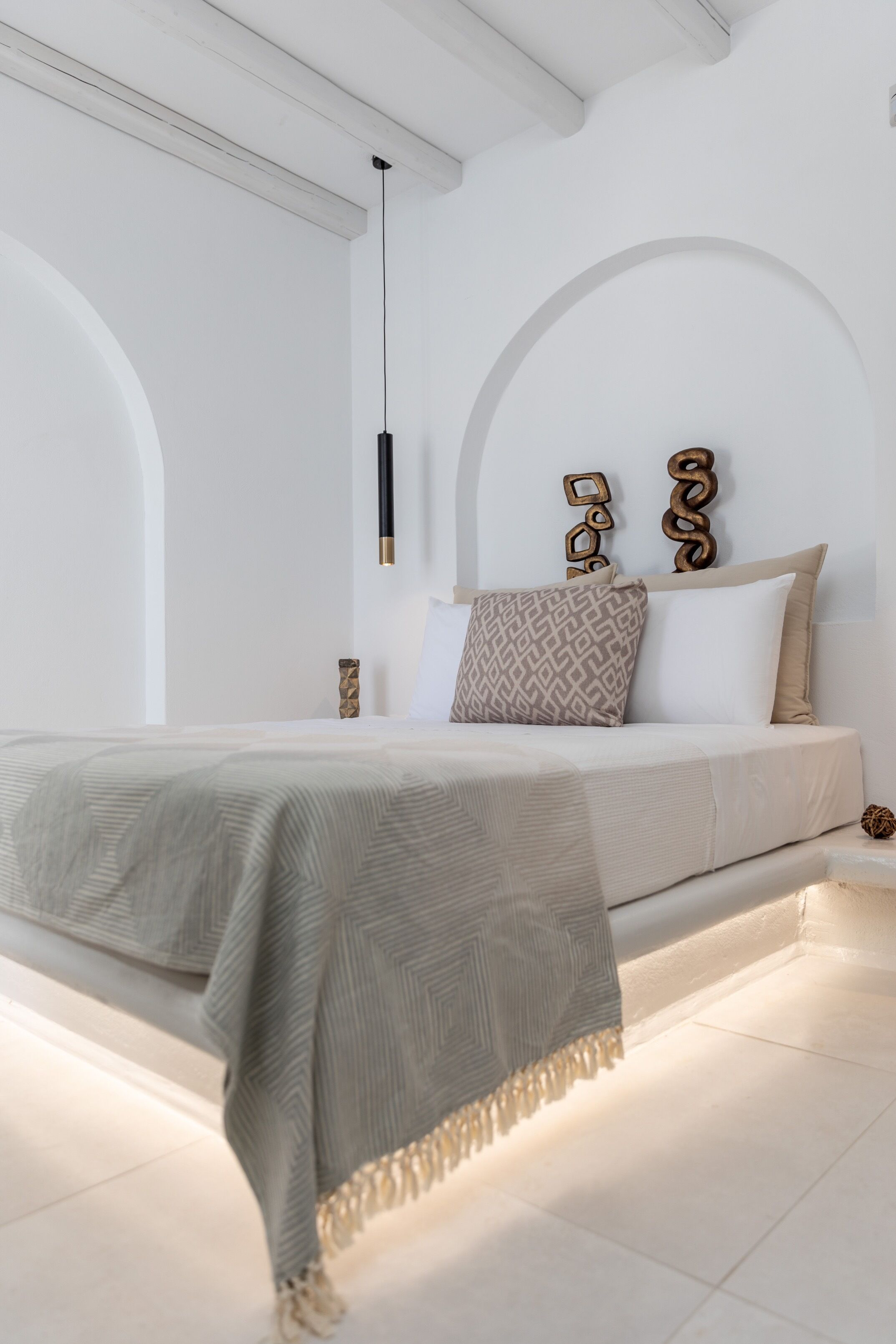 A modern bedroom with a large bed, a hanging light fixture, and decorative wall art.