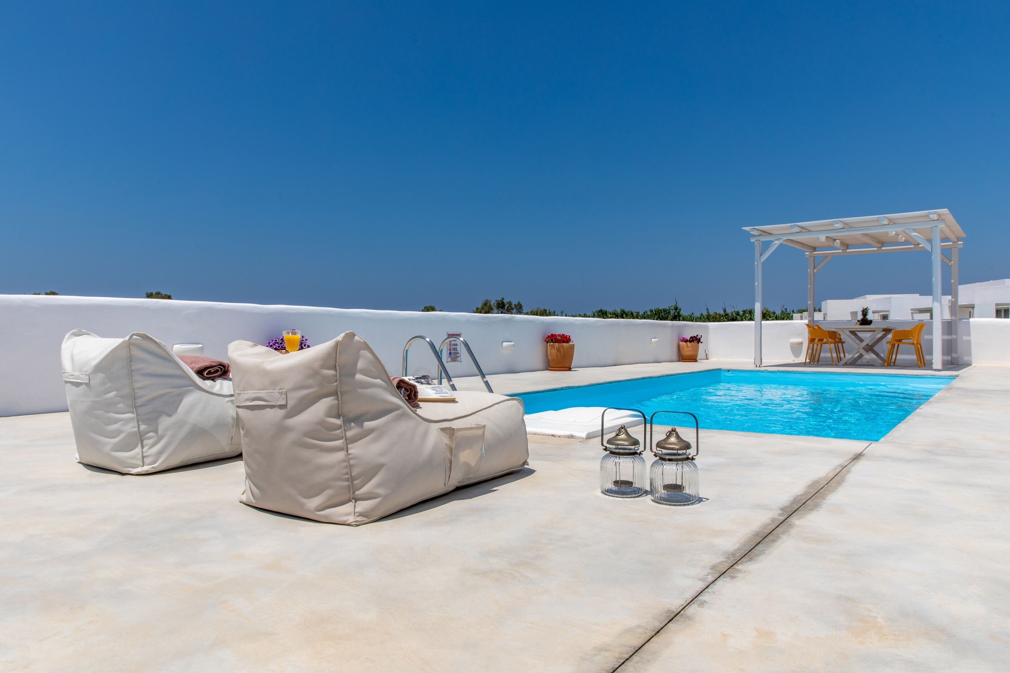 Un espace piscine aménagé sur le toit, avec des chaises longues, une pergola et une table entourée de chaises.