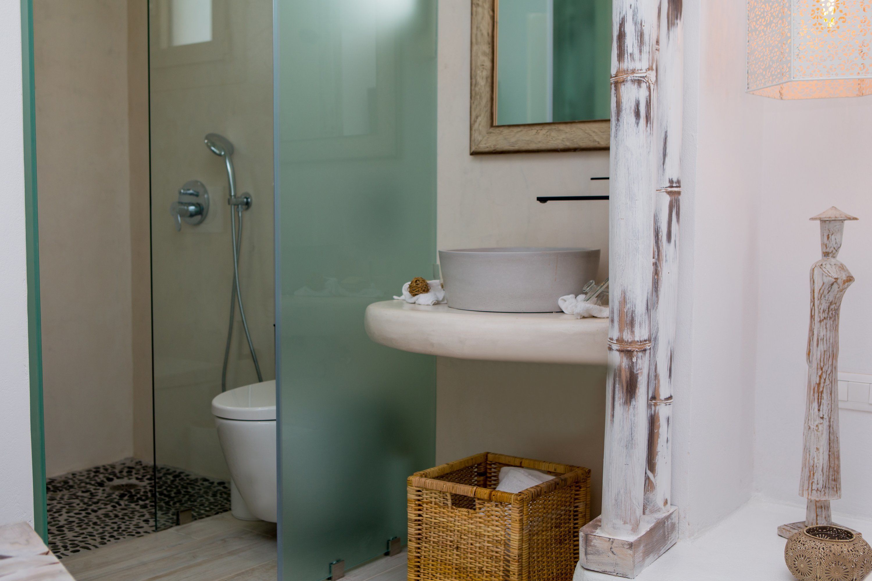 A bathroom with a glass shower enclosure, a white sink, and a decorative vase.