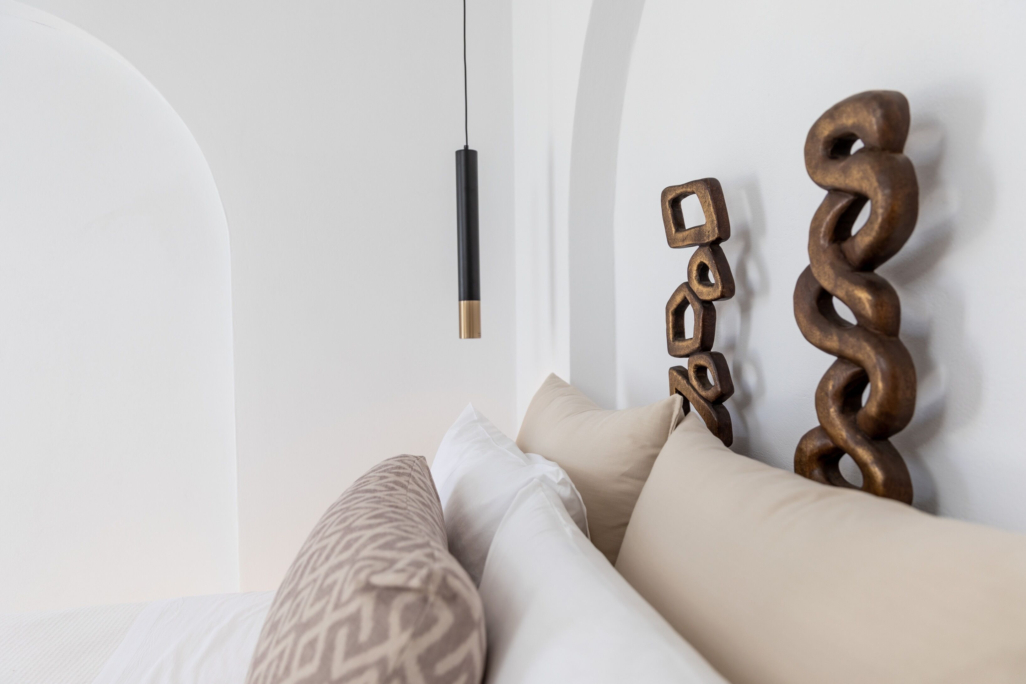 A neatly arranged bed with patterned pillows and a decorative wall piece.
