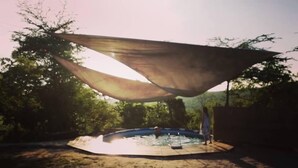A swimming pool with a shaded area and a person standing by the pool.