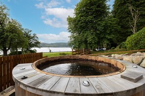 A wooden hot tub with a view of a lake and mountains in the background. - Altskeith Country House on Loch Ard (Stirling)