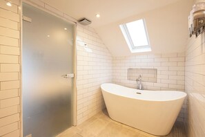 A modern bathroom with a freestanding bathtub, a skylight, and white tiled walls. - Altskeith Country House on Loch Ard (Stirling)