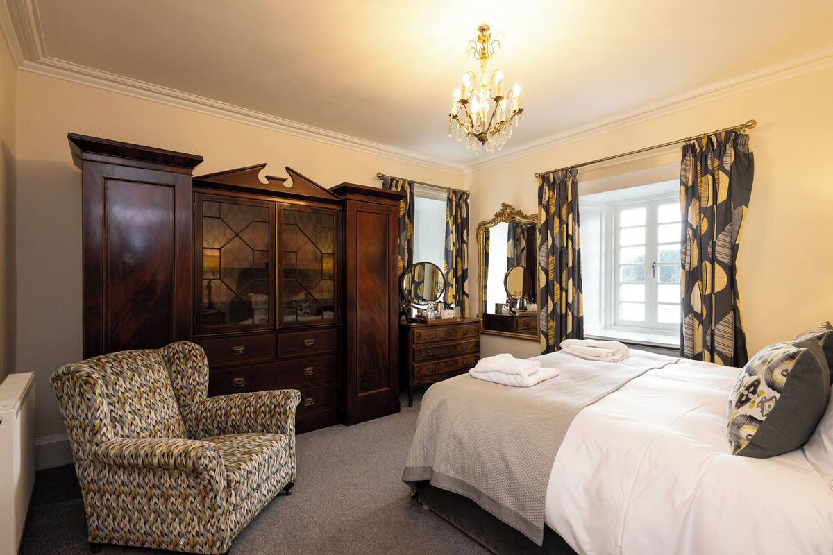 A bedroom with a bed, a dresser, a chair, and a mirror.
