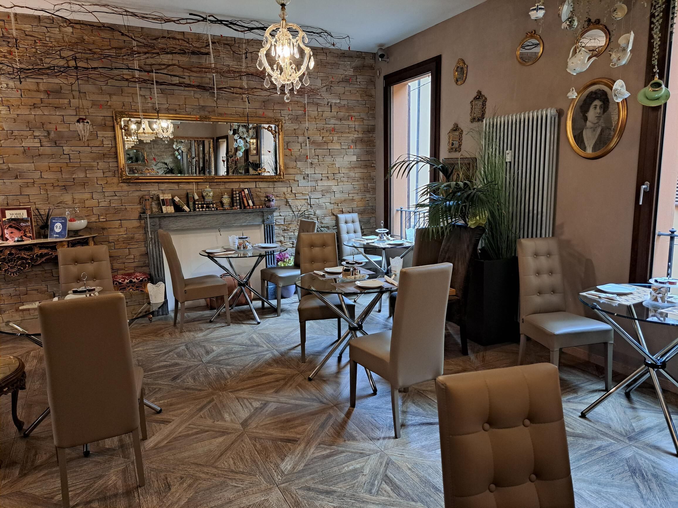 Een gezellige kamer met een bakstenen muur, een kroonluchter, een open haard en verschillende stoelen en tafels.