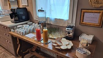 A breakfast bar with a coffee machine, a water dispenser, and various breakfast items including bread, juice, and cereal.