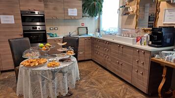 Una cocina moderna con armarios de madera, electrodomésticos de acero inoxidable y un comedor con mantel de encaje.