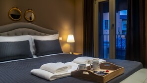 Une chambre d’hôtel avec un lit, deux miroirs, une table de chevet avec une lampe, un plateau avec des serviettes et des tasses, et une vue sur le balcon.