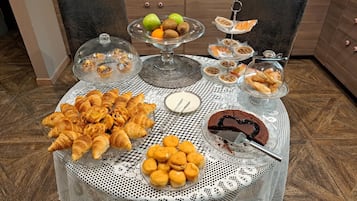 A table with various pastries, a cake, and a fruit bowl.