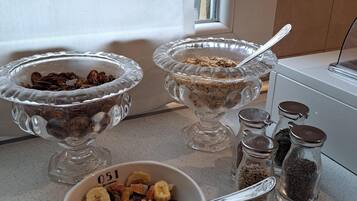 A kitchen counter with three glass bowls containing different food items, a bowl of mixed nuts, and several glass jars with lids.