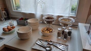 A kitchen counter with various bowls containing food items, a plate with utensils, and a window with a curtain.