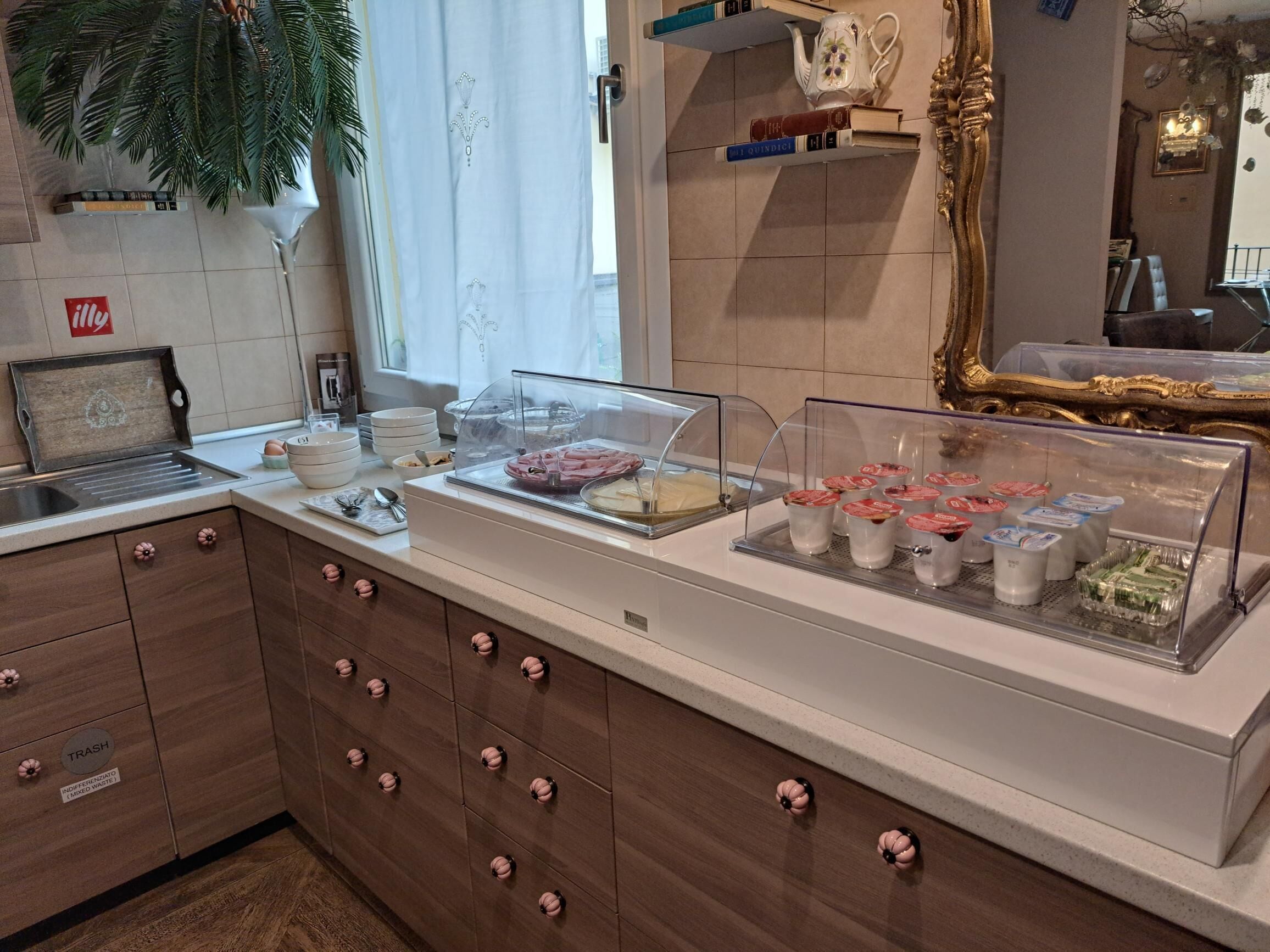 Un espace buffet pour le petit-déjeuner proposant divers aliments, une machine à café et un miroir décoratif.