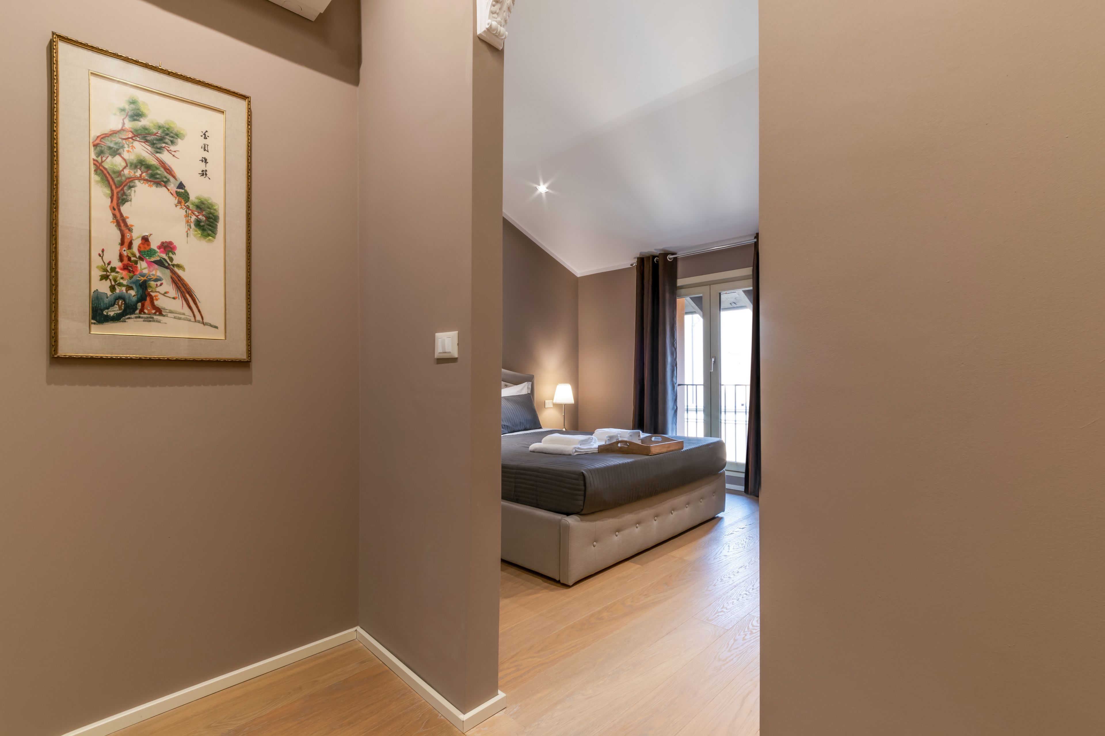 Una camera da letto con un letto, un comodino, una lampada e un quadro appeso al muro.