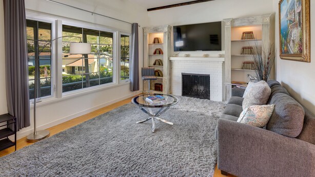 A living room with a fireplace, a sofa, a TV, and a bookshelf.