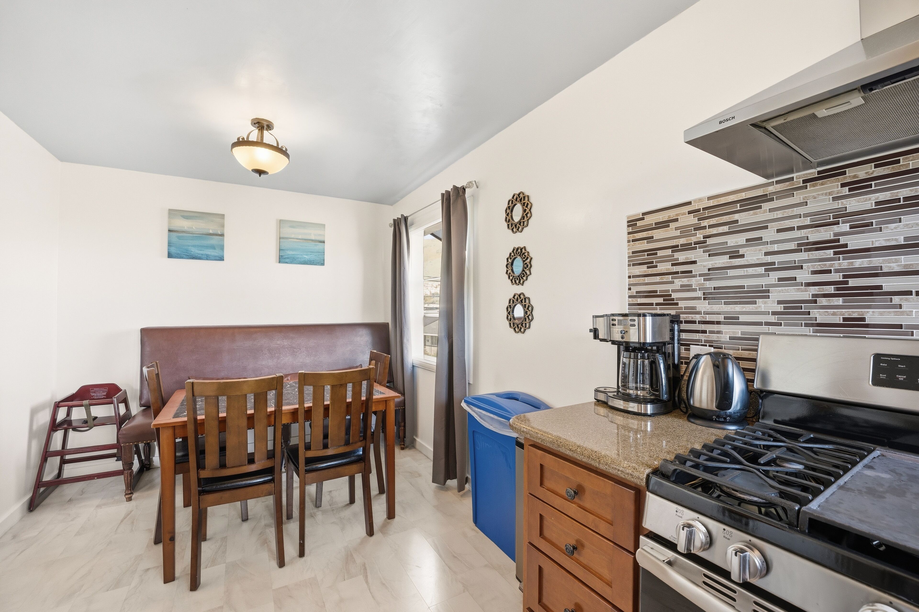 A kitchen with a gas stove, coffee maker, and a wall-mounted Bosch range hood.