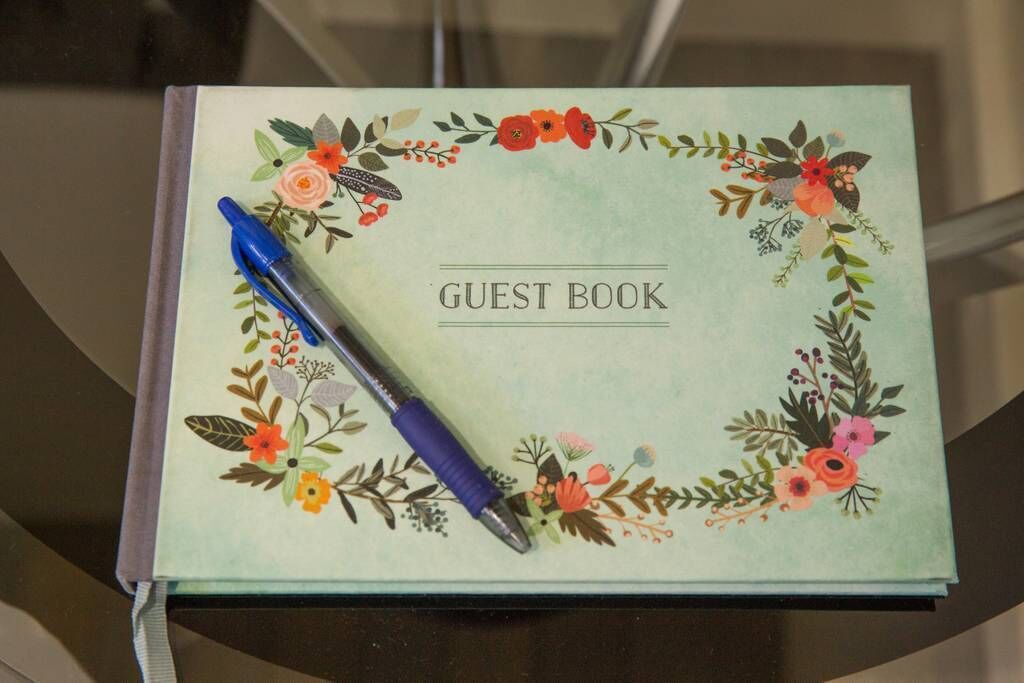 Ein Gästebuch mit floralem Muster und einem blauen Stift darauf.