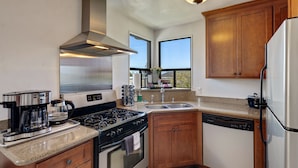 A modern kitchen with stainless steel appliances, wooden cabinets, and a large window providing natural light.