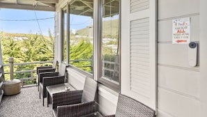 A covered porch with wicker furniture, a view of greenery, and a door marked with the number 732.