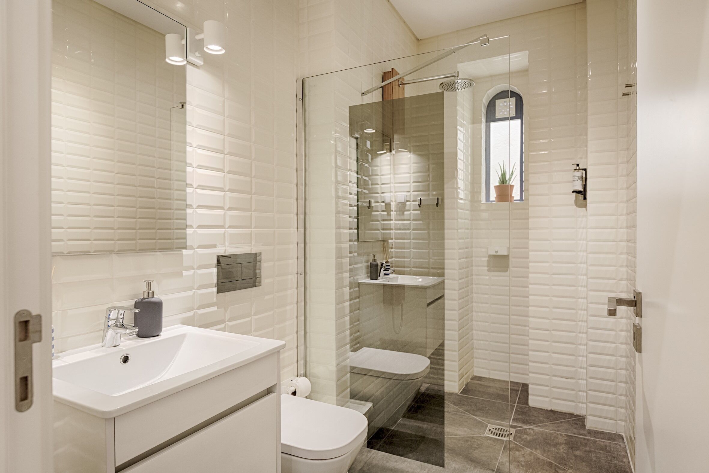 Une salle de bain moderne avec une douche à parois de verre, un lavabo blanc et des toilettes.