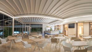 A modern indoor dining area with tables and chairs, a reception desk, and a glass wall offering a view of the outdoors. - Stele di Nora (Pula)