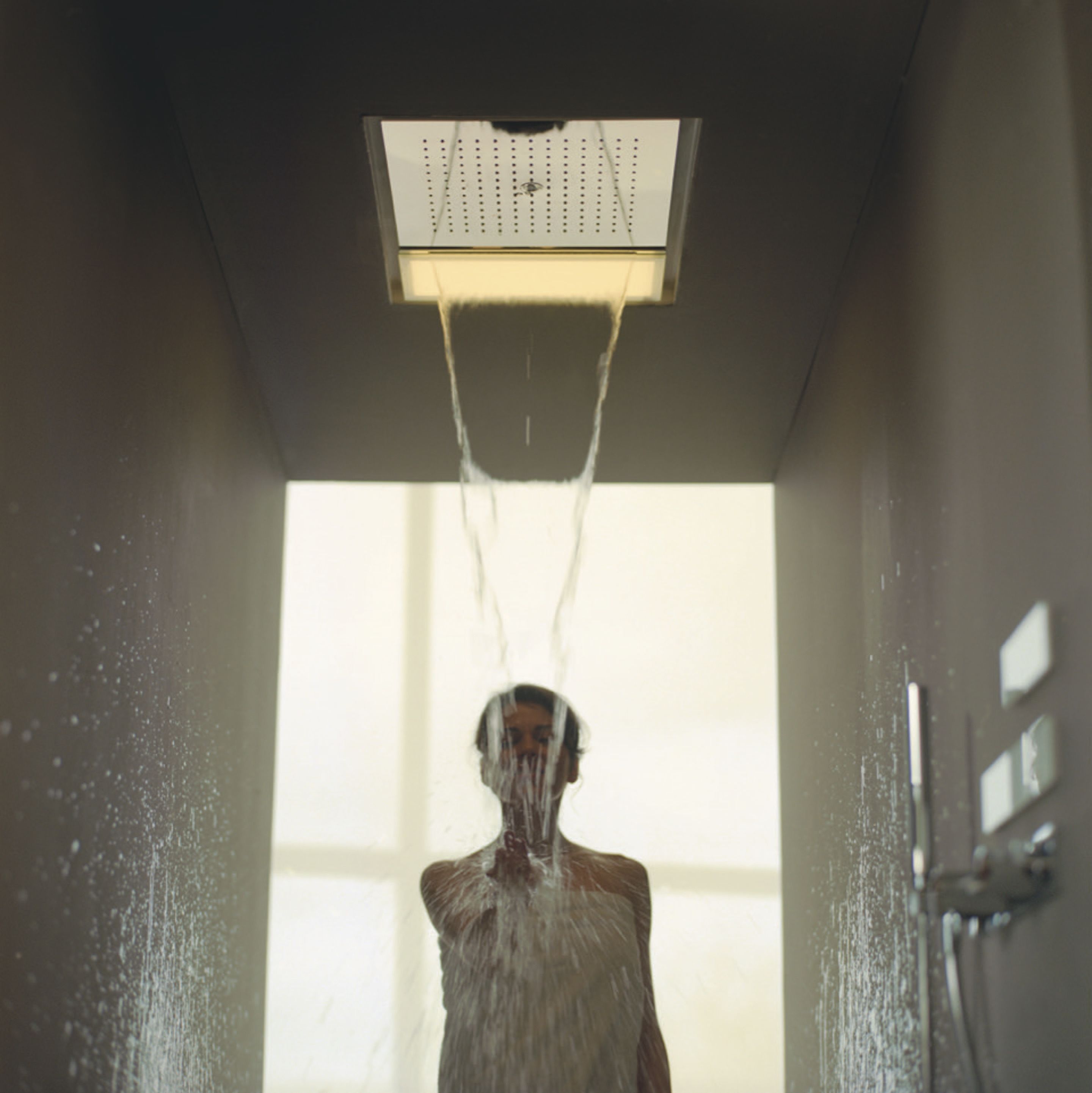 Una persona sotto la doccia con l'acqua che scorre da un soffitto.