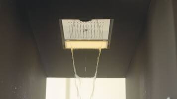 Una persona sotto la doccia con l'acqua che scorre da un soffitto.