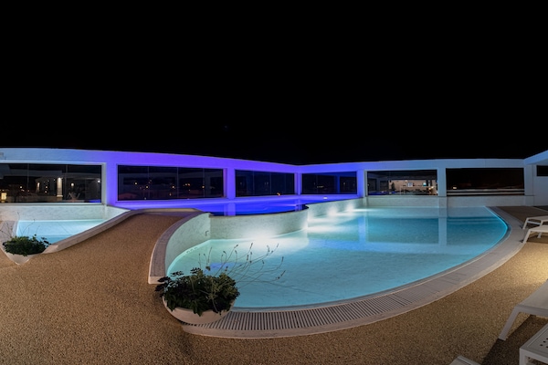 Una piscina al aire libre, sombrillas, sillones reclinables de piscina