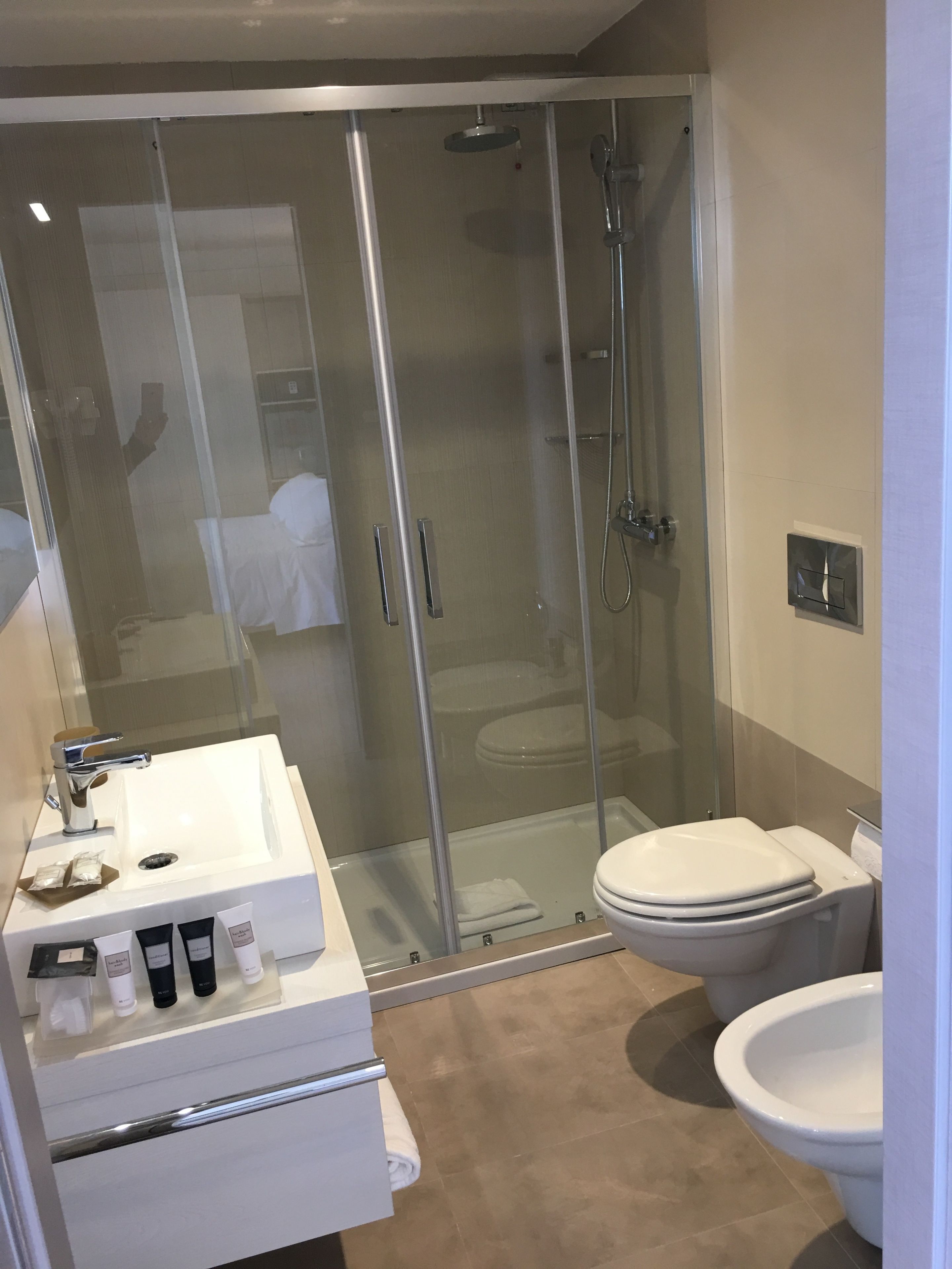 Un baño moderno con ducha de mampara de vidrio, un lavabo blanco y un inodoro.