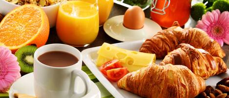 A breakfast tray with croissants, cheese, tomatoes, and a cup of coffee.
